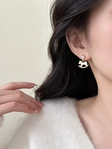Detail of elegant rocking horse pearl drop earrings worn by model for a luxury fashion look