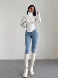 Dettaglio top bianco slim con collo alto caratterizzato da orlo curvo e maglia fine