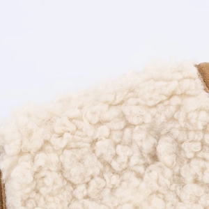 Close-up of the plush lamb wool lining on a cream-colored vest with soft texture