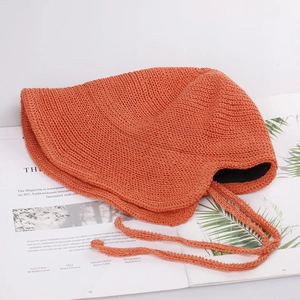 Detailed knit texture of orange sun hat with hollow crochet pattern and long chin strap