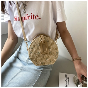 Detail of round straw crossbody bag with floral embroidery and brown PU strap