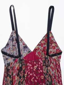 Dettaglio dell'abito floreale con scollo a V, decorazioni di perline e trame patchwork