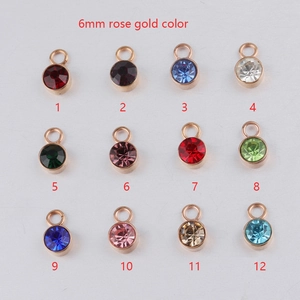Twelve 6mm rose gold bezel-set birthstone pendants with colorful zircon crystals on white