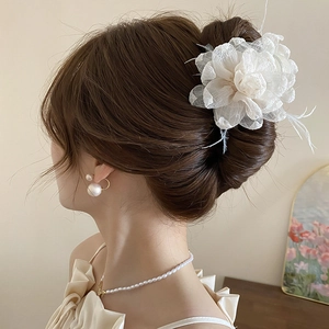 Detail einer eleganten Organza-Blumen-Haarklammer mit Perlen an einer Hochsteckfrisur
