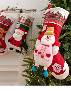 Chaussettes de Noël avec bonhomme de neige et Père Noël suspendues sur une cheminée
