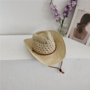 Detail of hollow woven texture on beige cowboy straw hat with brown adjustable strap