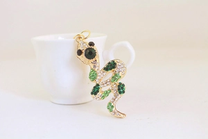 Detail of a golden snake keychain pendant set with sparkling green and clear rhinestones