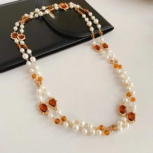 Detail of vintage double-layer pearl necklace with amber gemstone on a white surface