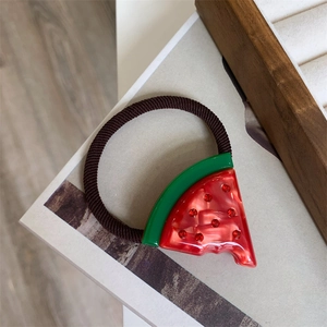 Detail of a handmade hair tie featuring a red watermelon charm with sparkling rhinestones