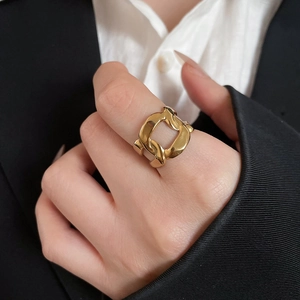 Detail of a golden double-loop ring worn by a model in professional black and white attire