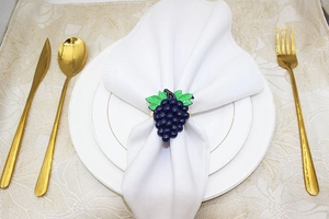 Macro detail of purple grape cluster napkin ring on a white napkin and plate