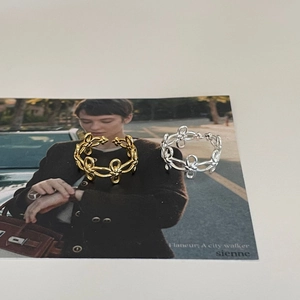 Detailed view of gold and silver intertwining knot rings on a minimalist postcard