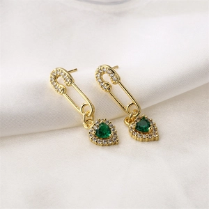 Détail de boucles d'oreilles épingle de sûreté avec cœur vert et strass blancs brillants