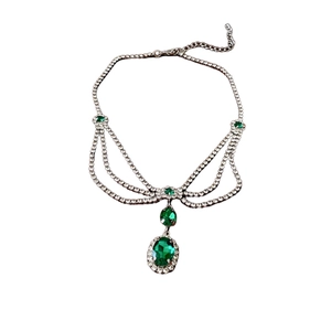 Multi-layer silver necklace with emerald oval stone and shimmering crystals on white background