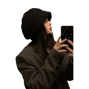 Minimalist black oversized knit beret for women shown on a model from a side profile angle