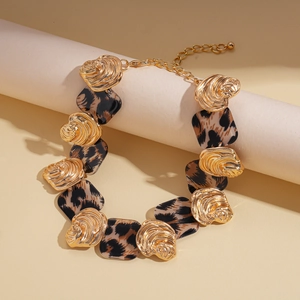 Detailed view of leopard print resin squares and gold textured metal links on necklace