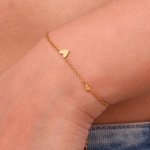 Detail of 18K gold plated stainless steel chain bracelet with double heart charms on wrist