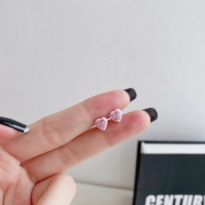 Close-up of pink heart stud earrings with enamel border and zircon center held by hand