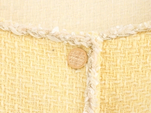 Detail of tweed fabric with gold button and white woven trim on a French style dress