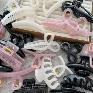 Detail of assorted jelly color hair claws in pink, white and black on a beige tray