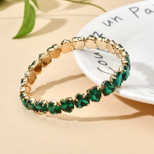 Elegant gold bracelet with emerald green heart-shaped crystals in a luxury design