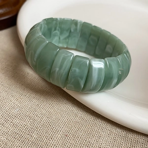 Detail view of light green resin elastic bracelet with marble texture on ceramic plate