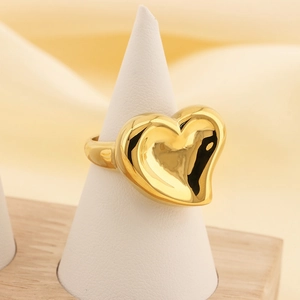 Detailed view of polished 18K gold heart ring on white stand with satin background