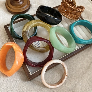 Macro view of assorted acrylic bangles in vintage tones on a wooden jewelry tray