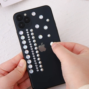 Detail of self-adhesive heart and pearl stickers applied on a black phone case