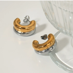 Close-up of two-tone C-shaped hoop earrings with polished gold and silver finish