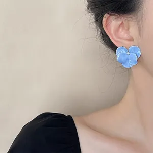 Detail showing blue flower earrings with rhinestone center on model for elegant style