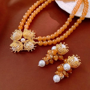 Detail of vintage double-layer beaded necklace and earrings set with floral gold pendant