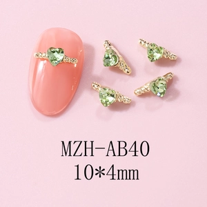 Macro view of light green heart crystal nail charms with gold wings, size 10x4mm