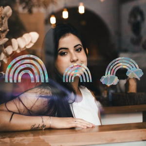 Three holographic rainbow prism window stickers on glass with a coffee shop background blur