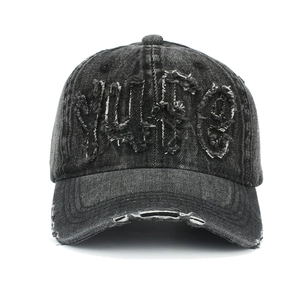 Détails de la broderie YUSE et finitions usées sur la casquette en denim délavé
