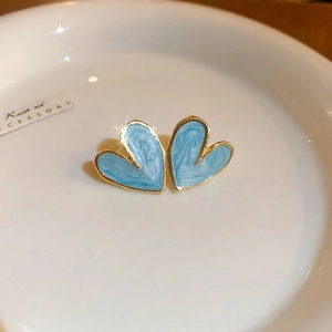 Detailed view of sky blue heart studs with gold edges and marble enamel finish on a plate