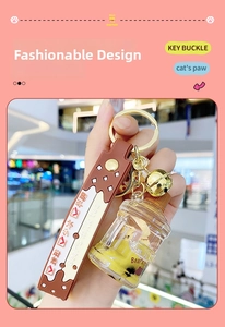 Detailed close-up of brown milk tea bear keychain with liquid floating charm and golden bell