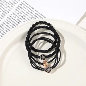 Detail of black elastic hair bands with gold beads and rhinestone heart charms on a tray