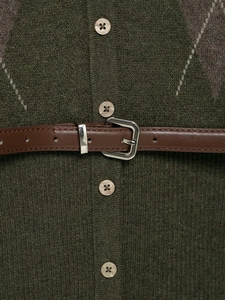 Dettaglio macro del cardigan verde oliva a rombi con cintura marrone e bottoni in perla