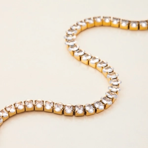 Macro shot of gold stainless steel tennis bracelet with sparkling oval cubic zirconia