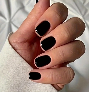 Glossy black square-round press-on nails shown in a close-up on a white fabric background