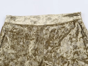 Detail of olive green velvet pants featuring metallic floral print and waist pocket
