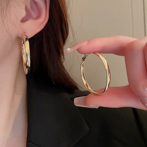 Detailed view of gold geometric hoop earrings showing model wear and hand-held details