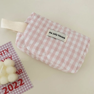 Close-up of pink checkered quilted vanity bag with durable woven strap and fabric label