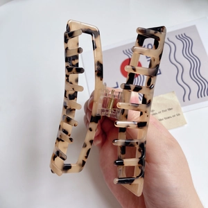 Detailed close-up of tortoise shell pattern on acetate hair claw clip held by hand
