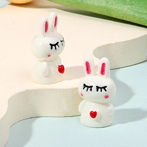 Close-up of small resin white bunny figurines with red hearts for DIY micro landscapes
