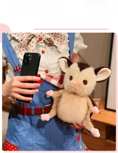Close-up of a plush sugar glider toy with brown fur and cute pink paws held by a model
