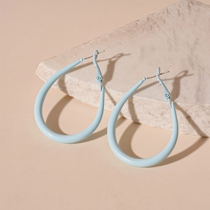 Detail view of light blue teardrop hoop earrings on a textured stone surface