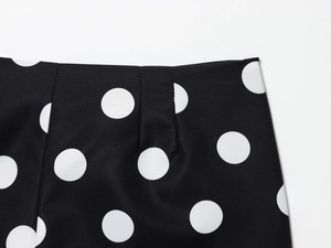 Close-up of waist stitching and white polka dot pattern on black high-waisted shorts