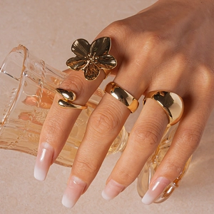 Detail of four-piece gold geometric ring set styled with a vintage glass for elegance